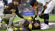Apr 20, 2025; Houston, Texas, USA;San Diego Padres first base coach David Macias (46) and Houston Astros second baseman Mauricio Dubon (14) check on San Diego Padres designated hitter Luis Arraez (4) as he  lies on the field after colliding with Houston Astros first baseman Christian Walker (8) (not pictured )on the first base line  in the first inning  at Daikin Park. Mandatory Credit: Thomas Shea-Imagn Images