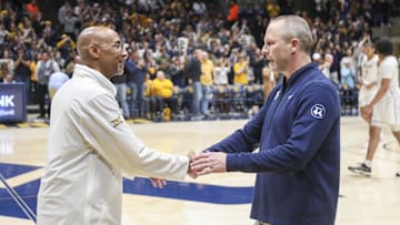 Mar 8, 2025; Morgantown, West Virginia, USA; West Virginia Mountaineers head coach Darian DeVries talks with UCF Knights head coach Johnny Dawkins after the game at WVU Coliseum. Mandatory Credit: Ben Queen-Imagn Images