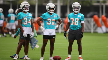 Jul 24, 2024; Miami Gardens, FL, USA; Miami Dolphins safety Jordan Colbert (34), safety Patrick McMorris (32), and safety Mark Perry (38) look on during training camp at Baptist Health Training Complex.