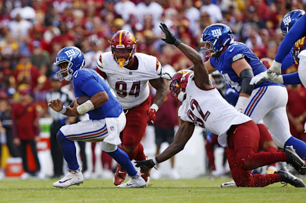 New York Giants quarterback Russell Wilson runs away from Washington Commanders defensive end Dorance Armstrong. 