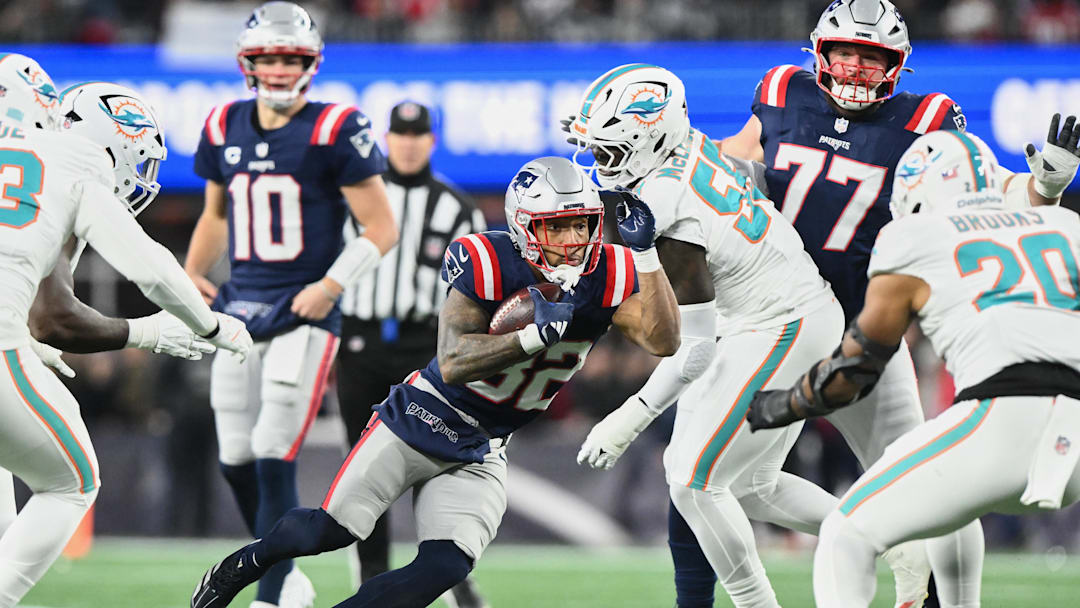 Jan 4, 2026; Foxborough, Massachusetts, USA; New England Patriots running back TreVeyon Henderson (32) runs the ball against Miami Dolphins center Aaron Brewer (55) during the first quarter at Gillette Stadium. Mandatory Credit: Brian Fluharty-Imagn Images