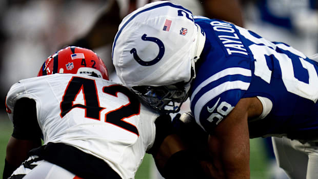 Colts running back Jonathan Taylor (blue jersey; white Guardian cap) tries to fight for extra yards while carrying the ball. 