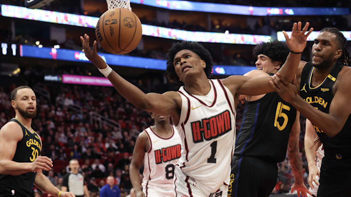 Feb 13, 2025; Houston, Texas, USA; Houston Rockets forward Amen Thompson (1) and Golden State Warriors forward Kevon Looney (5) reach for a rebound in the second  half at Toyota Center. Mandatory Credit: Thomas Shea-Imagn Images