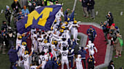 Michigan football players plant their team’s flag at midfield following their win over the Ohio State Buckeyes.