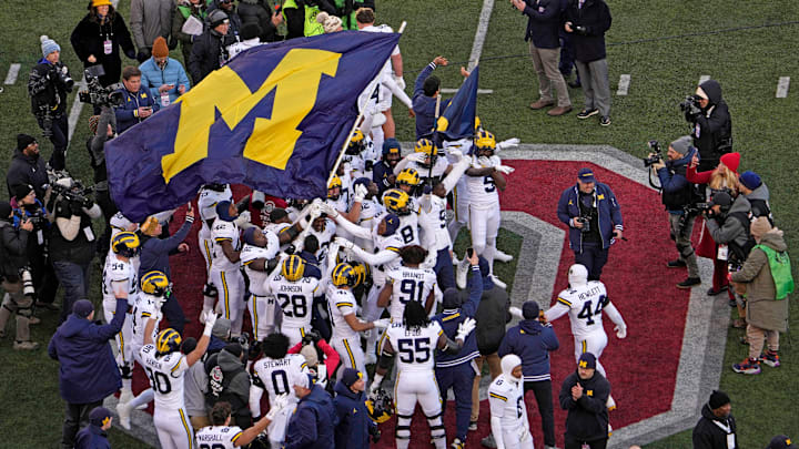 Michigan football players plant their team’s flag at midfield following their win over the Ohio State Buckeyes.