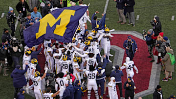 Michigan football players plant their team’s flag at midfield following Saturday’s NCAA Division I football game against the Ohio State Buckeyes at Ohio Stadium. The Michigan Wolverines won the game 13-10.