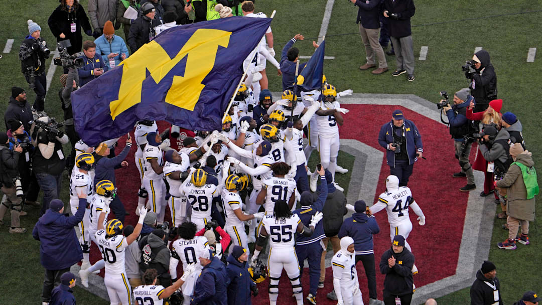 Michigan football players plant their team’s flag at midfield following Saturday’s NCAA Division I football game against the Ohio State Buckeyes at Ohio Stadium. The Michigan Wolverines won the game 13-10.