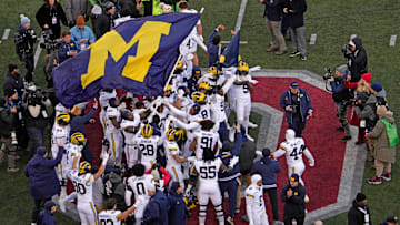 Michigan football players plant their team’s flag at midfield following Saturday’s NCAA Division I football game against the Ohio State Buckeyes at Ohio Stadium. The Michigan Wolverines won the game 13-10.
