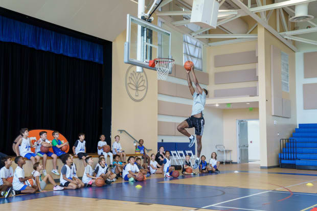 Spurs guard Blake Wesley dunks while a crowd of kids watches from beneath the basket at the Camana Bay and Jr. NBA/Jr. WNBA.