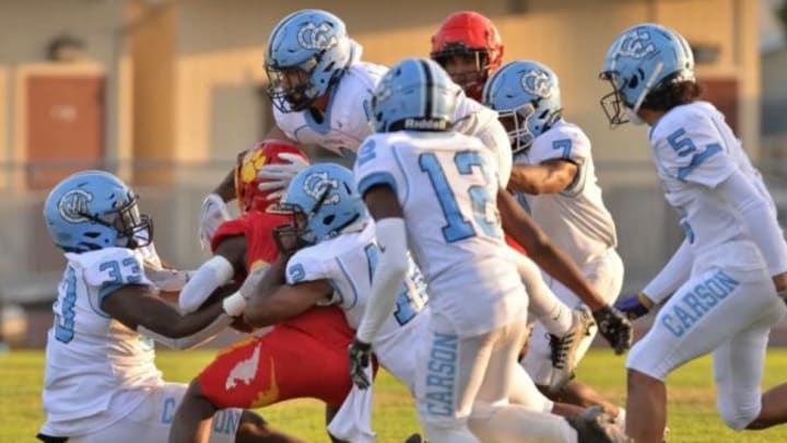 Carson High defense surrounds and brings down the ball carrier.