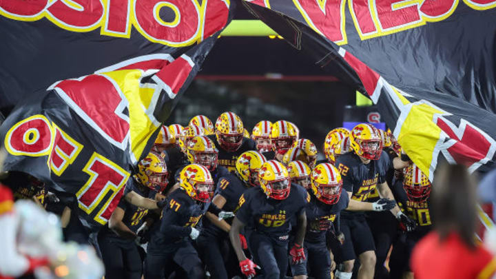 Mission Viejo football team bursts through a banner before kickoff.