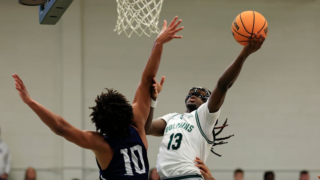 Jacksonville Dolphins guard Robert McCray V (13) drives the lane against North Florida Ospreys forward Josh Harris (10) during the first half of an NCAA men’s basketball matchup Saturday, Feb. 1, 2025 at Jacksonville University in Jacksonville, Fla. [Corey Perrine/Florida Times-Union]