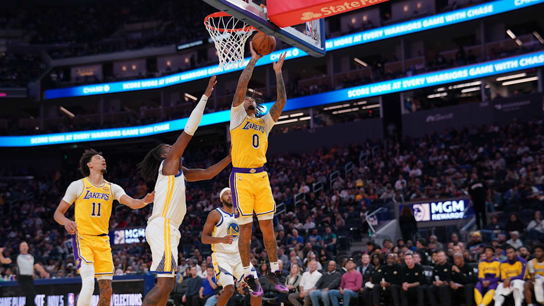 Oct 18, 2024; San Francisco, California, USA; Los Angeles Lakers guard Jalen Hood-Schifino (0) makes a basket in front of Golden State Warriors forward Kevon Looney (5) in the second quarter at the Chase Center. Mandatory Credit: Cary Edmondson-Imagn Images
