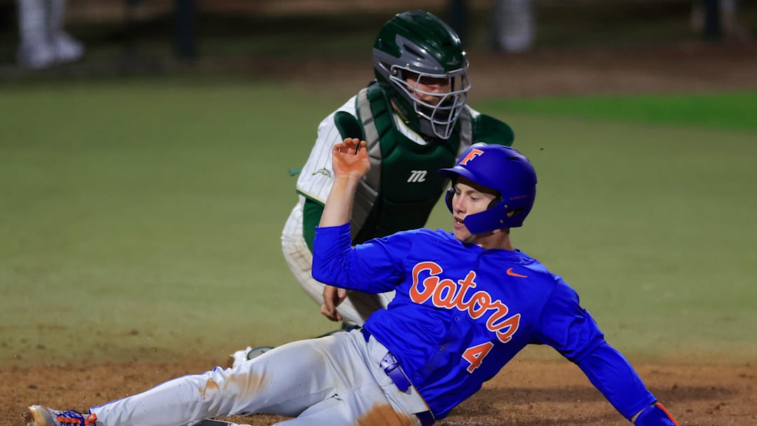 Florida infielder Cade Kurland (4) scores against Jacksonville catcher Nick DeLisi (38) during the eighth inning of an NCAA baseball matchup.