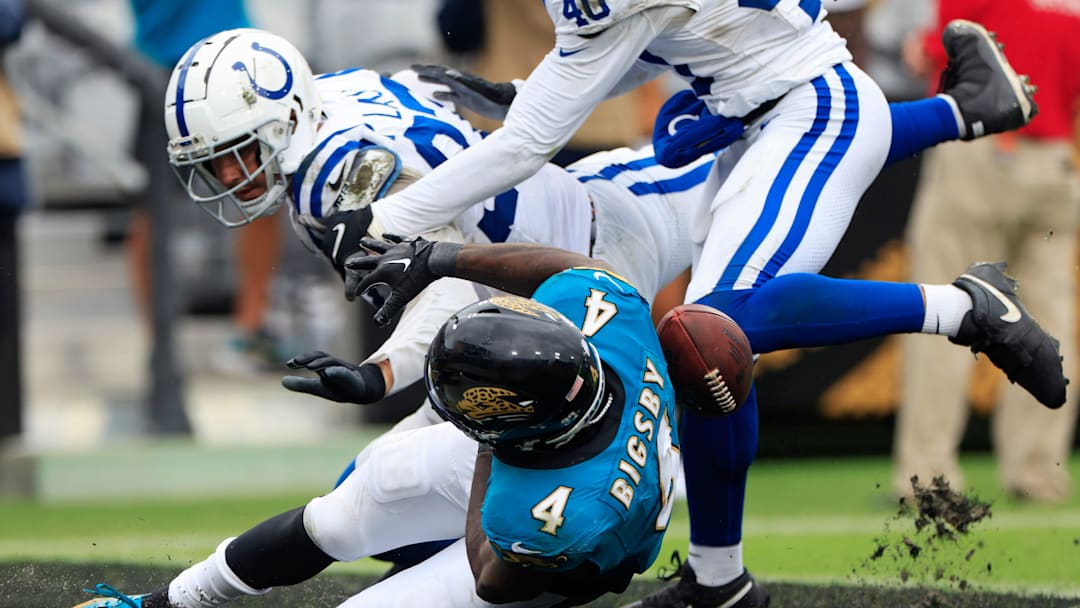 Jacksonville Jaguars running back Tank Bigsby (4) has the ball knocked away by Indianapolis Colts defensive end Laiatu Latu (97) that he would recover for a touchdown during the third quarter of an NFL football matchup Sunday, Oct. 6, 2024 at EverBank Stadium in Jacksonville, Fla. The Jaguars edged the Colts on a field goal 37-34. [Corey Perrine/Florida Times-Union]