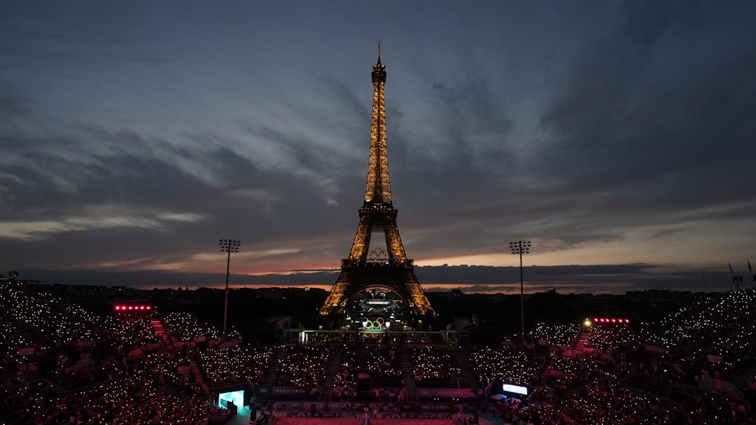 Jul 27, 2024; Paris, France; A general view of the Eiffel Tower at sunset as Kristen Nuss and Taryn Kloth (USA) and Heather Bansley and Sophie Bukovec (CAN) are introduced before a beach volleyball preliminary round match during the Paris 2024 Olympic Summer Games at Eiffel Tower Stadium.