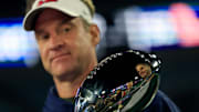 Lane Kiffin examines a trophy.