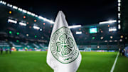 Detailed shot of a corner flag with the Celtic Glasgow coat of arms, illuminated stadium in the background. 