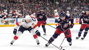 Blue Jackets defenseman Dante Fabbro tries to keep the puck away from Panthers forward Sam Reinhart.