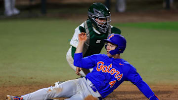 Florida infielder Cade Kurland (4) scores against Jacksonville catcher Nick DeLisi (38) during the eighth inning of an NCAA baseball matchup.