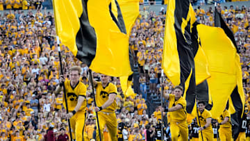 The Iowa Hawkeyes spirit squad runs flags across the field as the players swarm onto the field ahead of the football game against the Massachusetts Minutemen Sept. 13, 2025 at Kinnick Stadium in Iowa City, Iowa.