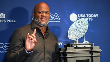 Oct 18, 2024; Austin, TX, USA; Vince Young stands with the AFCA Coaches’ Trophy at Vince Young Steakhouse. The trophy is presented by US LBM and awarded to the national champion and number one team in the US LBM coaches poll. Young and Charles both played for the Texas Longhorns and helped the team bring home the trophy at the end of the 2005 season. Texas is currently No. 1 in the latest poll. Mandatory Credit: Dustin Safranek-Imagn Images