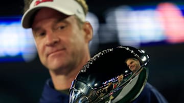 Lane Kiffin examines a trophy.