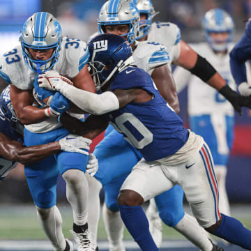 Aug 8, 2024; East Rutherford, New Jersey, USA; Detroit Lions running back Sione Vaki (33) carries the ball as New York Giants cornerback Darnay Holmes (30) and cornerback Alex Johnson (25) tackle during the first half at MetLife Stadium. Mandatory Credit: Vincent Carchietta-USA TODAY Sports