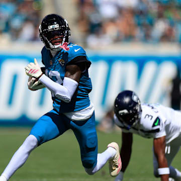 Jacksonville Jaguars wide receiver Travis Hunter (12) rushes for yards against Seattle Seahawks safety Nick Emmanwori (3) during the first quarter of an NFL football matchup, Sunday, Oct. 12, 2025, at EverBank Stadium in Jacksonville, Fla.