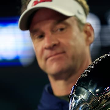 Lane Kiffin examines a trophy.