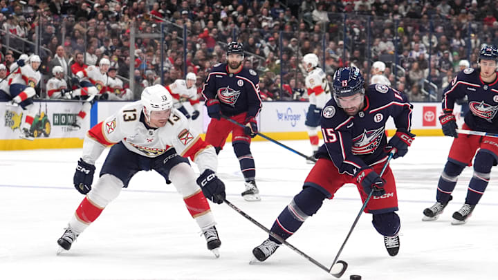 Blue Jackets defenseman Dante Fabbro tries to keep the puck away from Panthers forward Sam Reinhart.