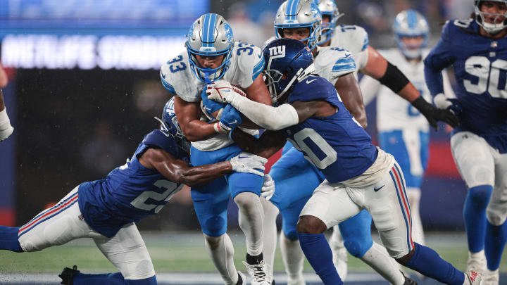 Aug 8, 2024; East Rutherford, New Jersey, USA; Detroit Lions running back Sione Vaki (33) carries the ball as New York Giants cornerback Darnay Holmes (30) and cornerback Alex Johnson (25) tackle during the first half at MetLife Stadium. Mandatory Credit: Vincent Carchietta-USA TODAY Sports