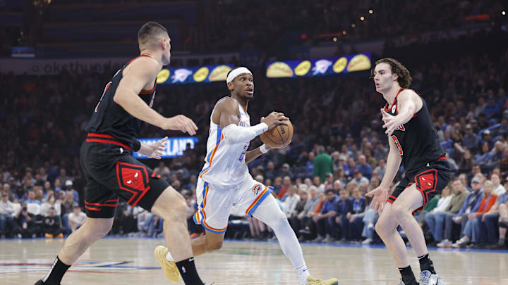 Mar 31, 2025; Oklahoma City, Oklahoma, USA; Oklahoma City Thunder guard Shai Gilgeous-Alexander (2) drives between Chicago Bulls center Nikola Vucevic (9) and guard Josh Giddey (3) during the first quarter at Paycom Center. Mandatory Credit: Alonzo Adams-Imagn Images