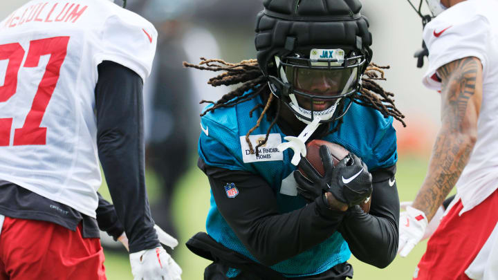 Jacksonville Jaguars running back D'Ernest Johnson (2) runs the ball between Tampa Bay Buccaneers cornerback Zyon McCollum (27) and safety Marcus Banks (39) during a combined NFL football training camp session between the Tampa Bay Buccaneers and Jacksonville Jaguars Thursday, Aug. 15, 2024 at EverBank Stadium’s Miller Electric Center in Jacksonville, Fla. [Corey Perrine/Florida Times-Union]