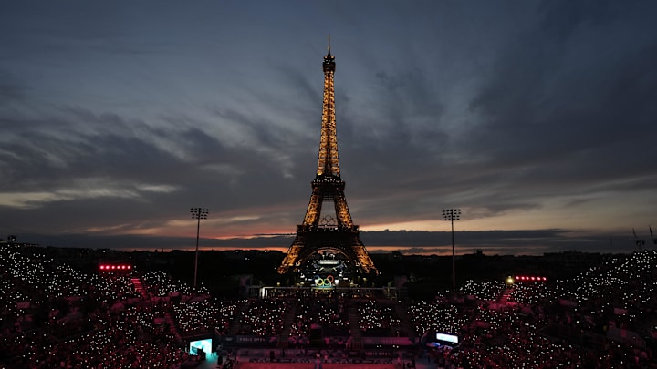 Jul 27, 2024; Paris, France; A general view of the Eiffel Tower at sunset as Kristen Nuss and Taryn Kloth (USA) and Heather Bansley and Sophie Bukovec (CAN) are introduced before a beach volleyball preliminary round match during the Paris 2024 Olympic Summer Games at Eiffel Tower Stadium.