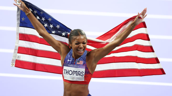 American runner Gabby Thomas poses with the American flag after winning the gold medal in the 200-meter race at the Paris Olympics.