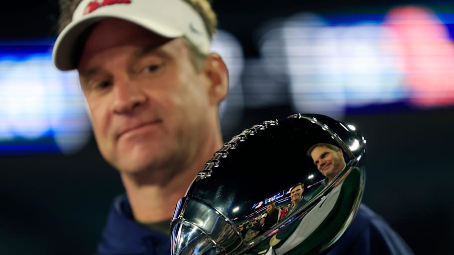 Lane Kiffin examines a trophy. | Corey Perrine/Florida Times-Union / USA TODAY NETWORK via Imagn Images