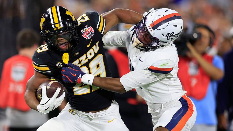 Missouri Tigers running back Ahmad Hardy fends off Virginia Cavaliers cornerback Emmanuel Karnley.