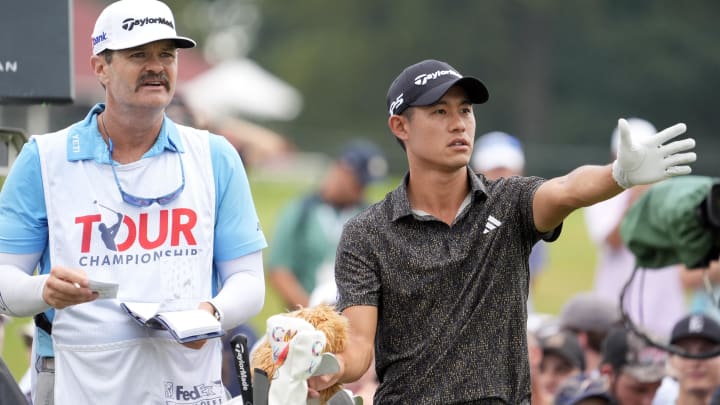 Collin Morikawa and his caddie plan a shot