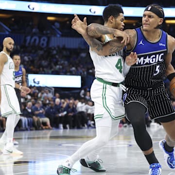 Nov 7, 2025; Orlando, Florida, USA; Orlando Magic forward Paolo Banchero (5) is guarded by Boston Celtics guard Anfernee Simons (4) in the fourth quarter  at Kia Center. Mandatory Credit: Nathan Ray Seebeck-Imagn Images