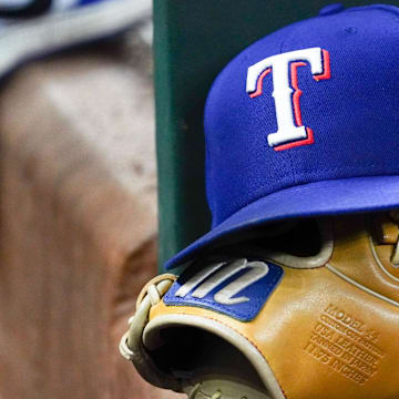 A Texas Rangers cap and baseball mitt sit on the dugout steps during a game against the Athletics at Globe Life Field. 