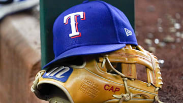 A Texas Rangers cap and baseball mitt sit on the dugout steps during a game against the Athletics at Globe Life Field. 