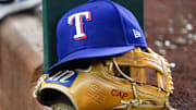 A Texas Rangers cap and baseball mitt sit on the dugout steps during a game against the Athletics at Globe Life Field. 