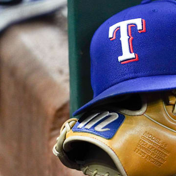A Texas Rangers cap and baseball mitt sit on the dugout steps during a game against the Athletics at Globe Life Field. 