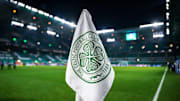 Detailed shot of a corner flag with the Celtic Glasgow coat of arms, illuminated stadium in the background. 