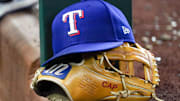 A Texas Rangers cap and baseball mitt sit on the dugout steps during a game against the Athletics at Globe Life Field.