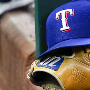 A Texas Rangers cap and baseball mitt sit on the dugout steps during a game against the Athletics at Globe Life Field. 