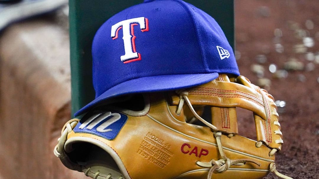 A Texas Rangers cap and baseball mitt sit on the dugout steps during a game against the Athletics at Globe Life Field.