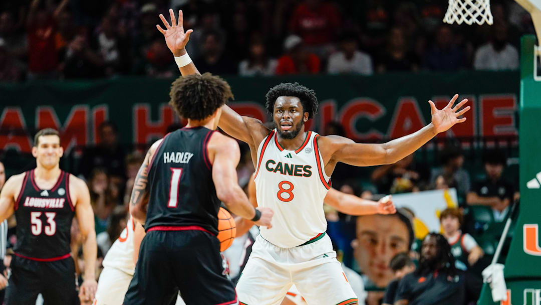 Mar 7, 2026; Coral Gables, Florida, USA; Miami Hurricanes center Ernest Udeh Jr. (8) defends against Louisville Cardinals guard J'vonne Hadley (1) during the second half at Watsco Center. Mandatory Credit: Jeff Romance-Imagn Images