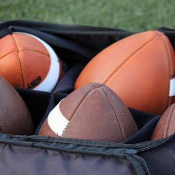 Footballs rest in a bag at a high school football game